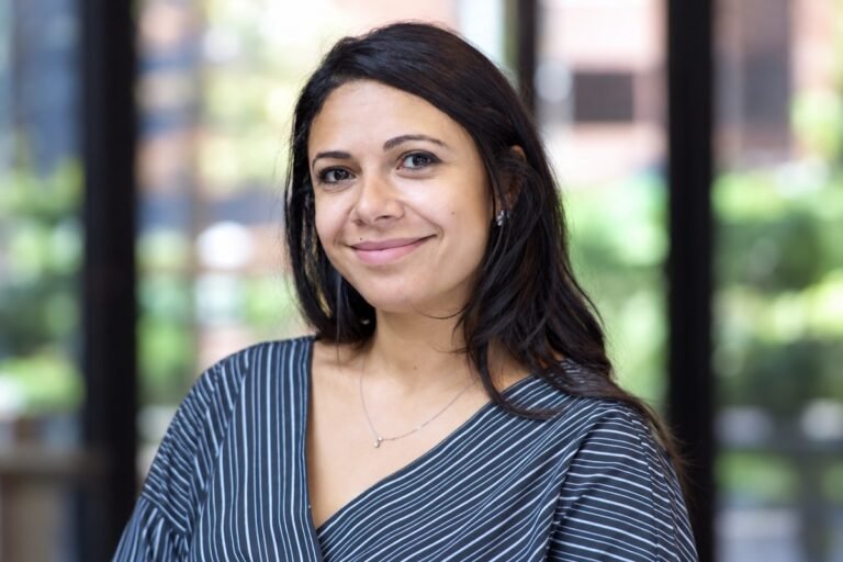 Sarah Hashem smiling in a striped blouse against a softly blurred background